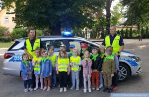 funkcjonariusze z Komendy Powiatowej Policji w Wołowie z przedszkolakami na tle radiowozu oznakowanego