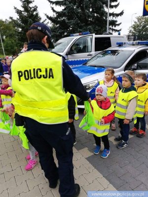 Funkcjonariuszka rozdająca dzieciom elementy odblaskowe