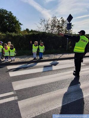 funkcjonariusz uczący przedszkolaków bezpiecznie przechodzić przez przejście dla pieszych