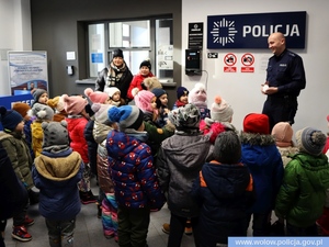 grupa dzieci stoi przed policjantem w mundurze w pomieszczeniu