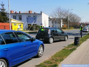 umundurowany funkcjonariusz Policji zatrzymujący za pomocą tarczy do zatrzymywania pojazdów pojazd do kontroli drogowej