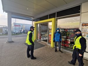 umundurowany policjancie legitymują osobę przed wejściem do sklepu